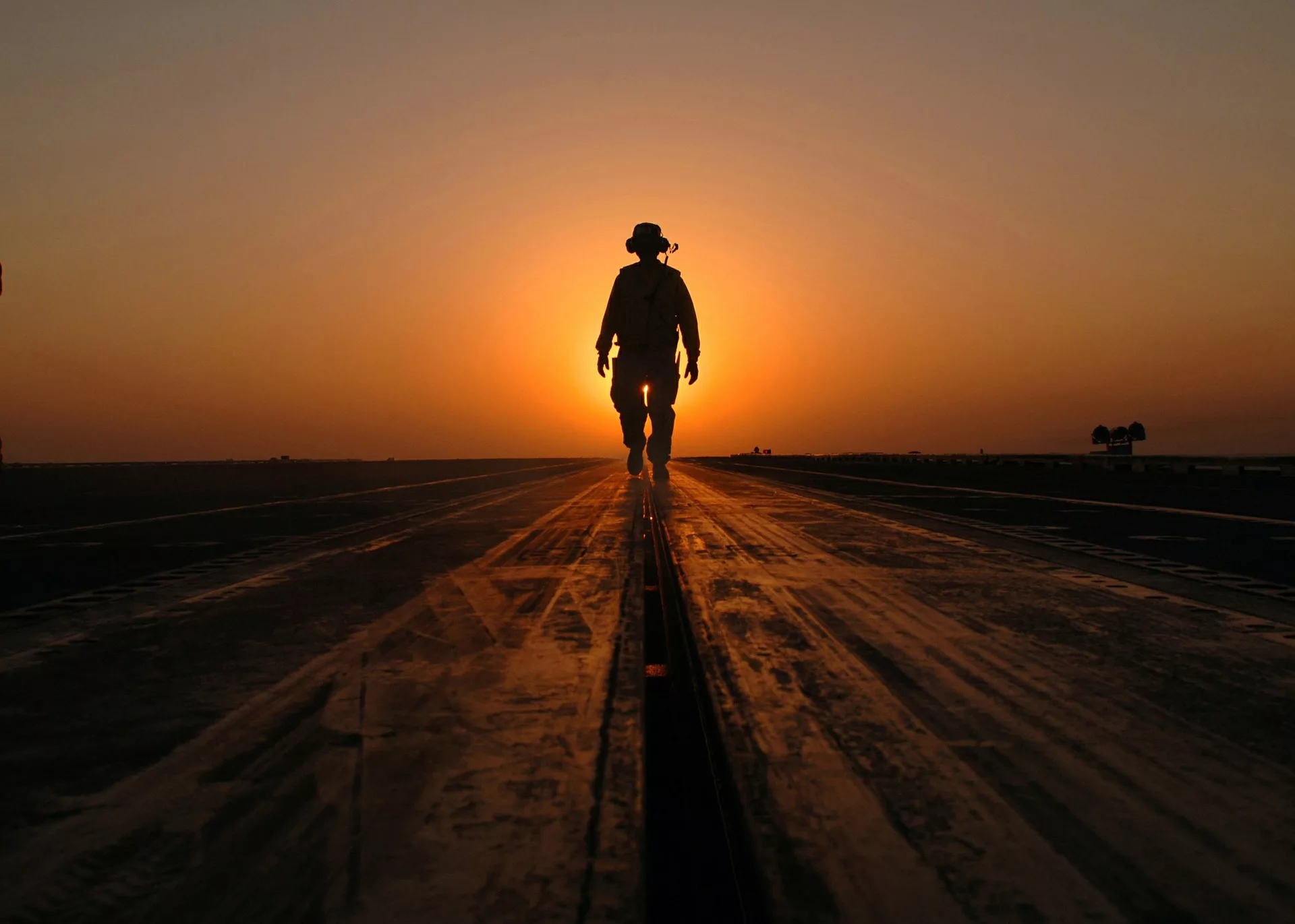 Silhouetted person walking on deck at sunset