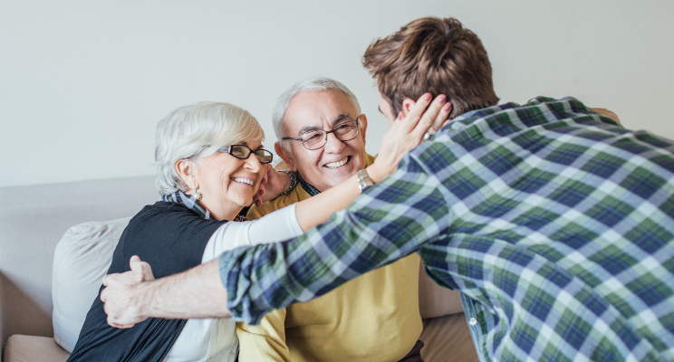 Young man hugging smiling elderly couple