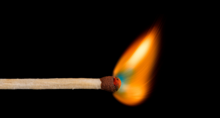 Burning matchstick with bright orange flame