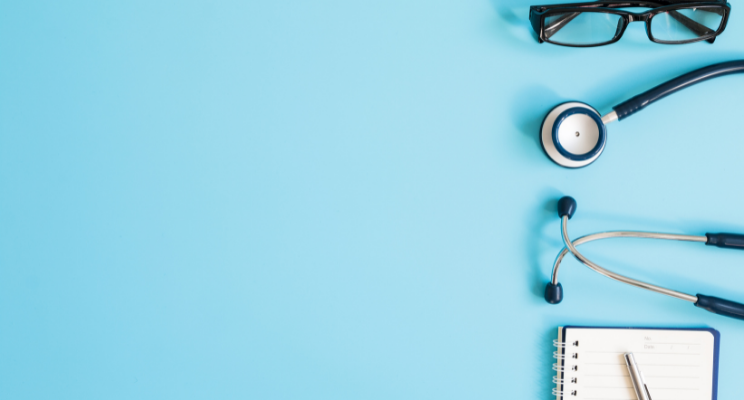 Medical stethoscope and glasses beside notebook