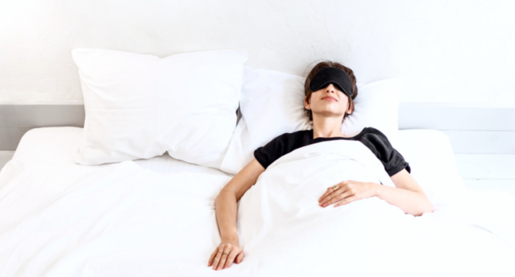 Person sleeping in bed wearing black sleep mask