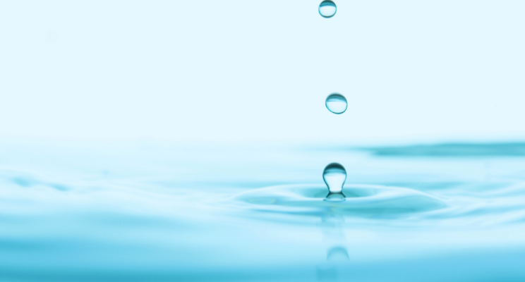 Water droplets creating ripple on blue surface