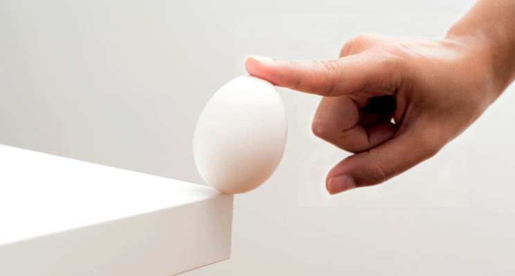 Finger balancing egg on table corner