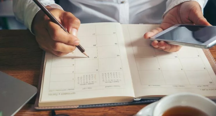 Close-up shot of hands writing on calendar book