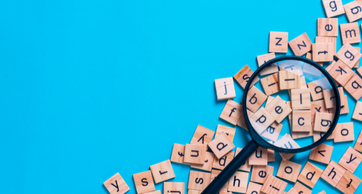 Magnifying glass over scattered wooden letter tiles