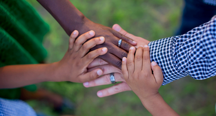 Several hands on top of each other of different ethnic origin