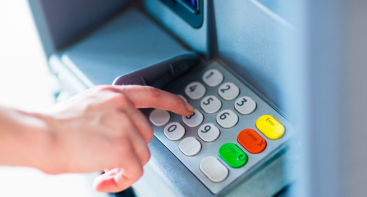 Hand entering PIN on ATM keypad